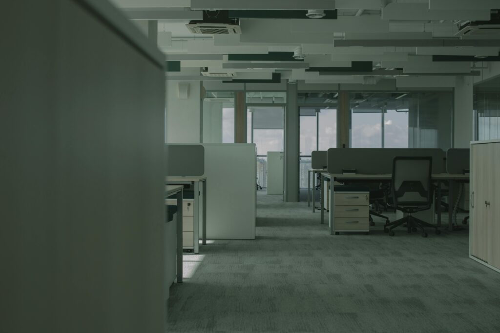 Spacious empty office featuring modern desks, chairs, and partitions.